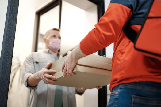 A deliveryman hands over pizza boxes while wearing a mask, highlighting contactless delivery during the pandemic.